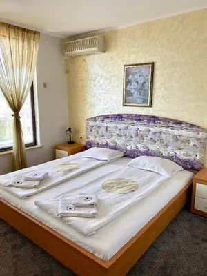 a bedroom with a large bed with a purple headboard at Family Hotel The Golden fish in Sozopol