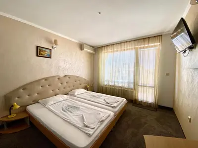 a bed in a room with a large window at Family Hotel The Golden fish in Sozopol