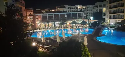 a large swimming pool with blue water at night at Pollo Resort, Summer Wind Apartaments in Sunny Beach