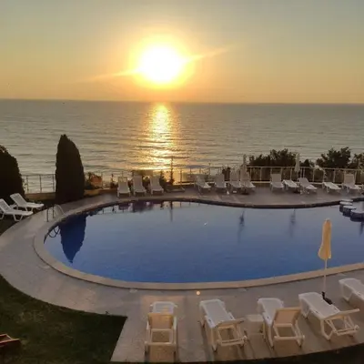 a swimming pool with chairs and the ocean at sunset at Silver A28 in Byala