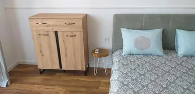 a bedroom with a wooden cabinet next to a bed at Atlantis Atmosphere Apartment in Burgas City
