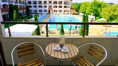 a balcony with a table and chairs with a view of a pool at Апартамент Сънрайз Обзор - Apartment Sunrise Obzor in Obzor