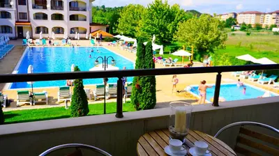 a balcony with a table and a view of a pool at Апартамент Сънрайз Обзор - Apartment Sunrise Obzor in Obzor