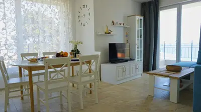 a living room with a dining table and a tv at Апартаменти Атеа на плажа - Apartments Atea on the beach in Obzor