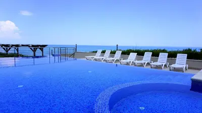 a swimming pool with chairs and the ocean in the background at Бяла Клиф Форест - Byala Cliff Forest in Byala