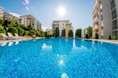 a large blue swimming pool with two buildings at Fort Noks - Menada Apartments in Sveti Vlas