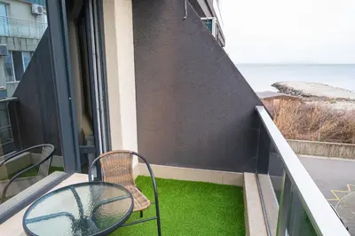 a balcony with two chairs and a table and a window at Modern Apartment for 4 Guests Sea View & Free Parking in Pomorie