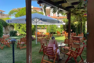 a woman sitting at a table under an umbrella at Apartment Doris in Sunny Beach