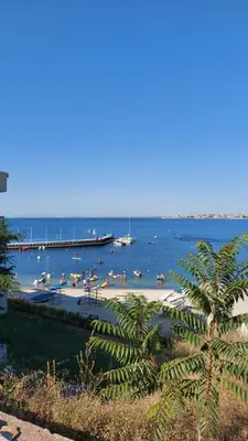 a beach with people and boats in the water at Акротирия Фешева in Nesebar