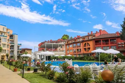 a resort with a pool and chairs and buildings at Luxury First Line apartment with pool by the sea in Nesebar