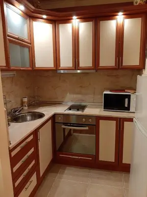 a kitchen with wooden cabinets and a sink and a microwave at Апартамент Златна дюна-Фешева in Nesebar