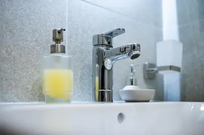 a sink with a faucet and a bottle of soap at Smart Central Apartment in Varna City