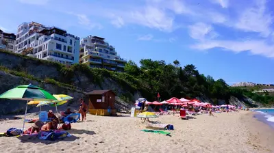 a group of people sitting on a beach with umbrellas at Byala Vista Beach Apartments D - Бяла Виста Бийч Апартментс Д in Byala