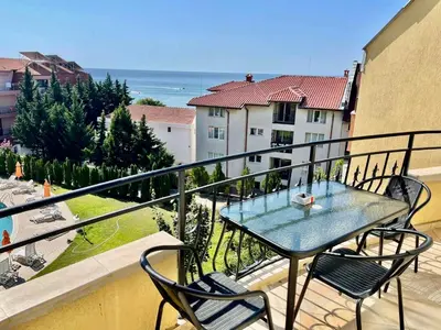 a table and chairs on a balcony with a view of the ocean at Апартамент Свети Влас in Sveti Vlas