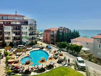 a view of a swimming pool with umbrellas and the ocean at Апартамент Свети Влас in Sveti Vlas