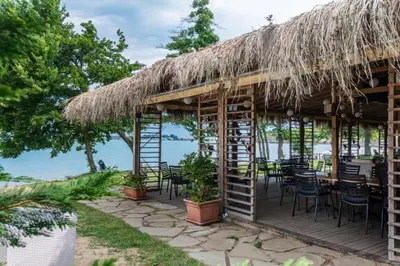 a restaurant with a thatched roof and tables and chairs at Sunrise - Apartment 41,Santa Marina, Sozopol in Sozopol