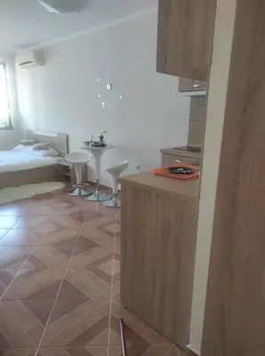 a room with a bed and a kitchen with a table at Apartament in sun waves in Burgas City