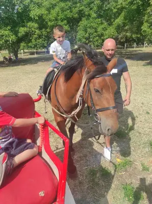 a man and a young boy riding a horse at Apartament in sun waves in Burgas City