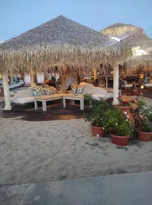 a resort with a straw umbrella and chairs on the beach at Apartament in sun waves in Burgas City