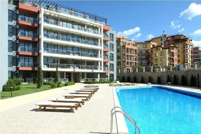a swimming pool with lounge chairs and a building at Apartament in sun waves in Burgas City