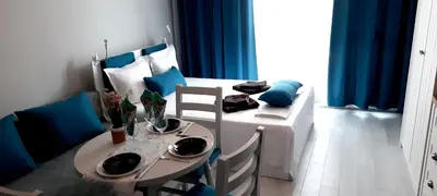 a room with a table and chairs and a room with blue curtains at A-19 Sea View Studio-Apartmen Sarafovo in Burgas City