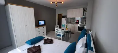 a bedroom with a bed with blue pillows and a kitchen at A-19 Sea View Studio-Apartmen Sarafovo in Burgas City