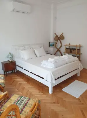 a large white bed in a room with wooden floors at Апартамент BOHO CHIC Free parking in Varna City