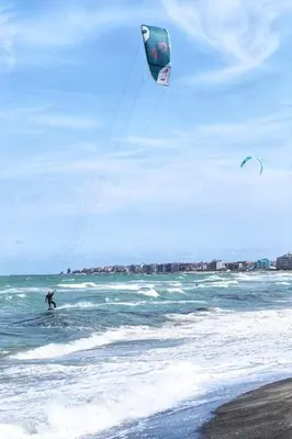 a person kite surfing in the ocean on the beach at Уютная квартира - студия в Старом Поморие, Болгария in Pomorie