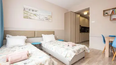 a bedroom with two beds and a table and a desk at Студио Булаир 1 с безплатен паркинг in Burgas City