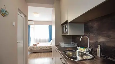 a kitchen with a sink and a bed in the window at Студио Булаир 1 с безплатен паркинг in Burgas City
