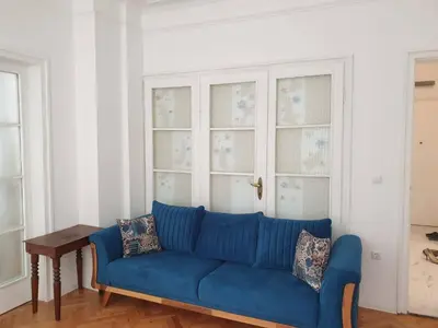 a blue couch in a living room with windows at Апартамент BOHO CHIC 2 Free parking in Varna City