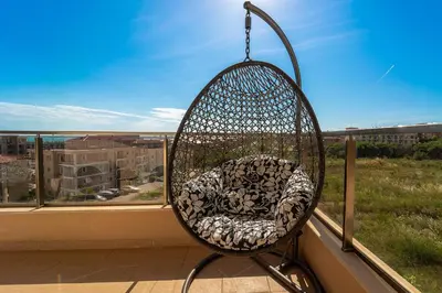 a swing chair sitting on a balcony with a window at Premium complex Millennium 2 - Family apartment & Spa in Sveti Vlas