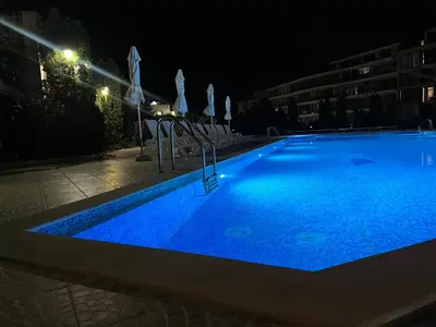 a large blue swimming pool at night at Sun Wave Apartament in Sveti Vlas