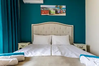 a bedroom with a bed with a blue wall at Touristic Complex Hacienda Beach Apartments Sozopol in Sozopol