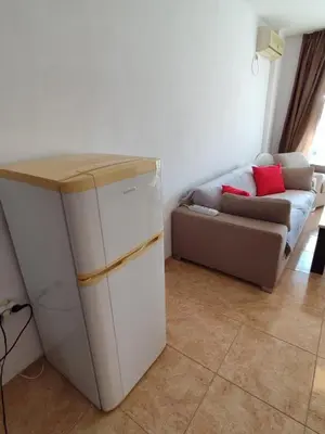 a small refrigerator in a room with a couch at Midia Grand Resort, Terrassen Paradies Apartment in Aheloy