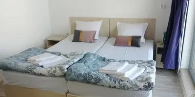 two beds in a room with a couch and pillows at апартамент на брега на морето Бургас - Сарафово in Burgas City