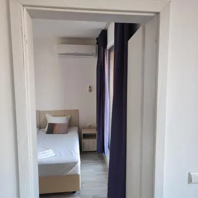 a small bedroom with a bed and a hallway at апартамент на брега на морето Бургас - Сарафово in Burgas City