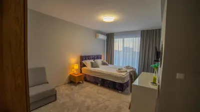 a bedroom with a bed and a chair and a window at La Mansión in Lozenets
