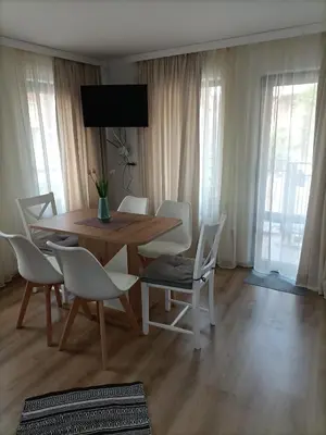 a dining room with a wooden table and white chairs at DAMARIS in Sozopol