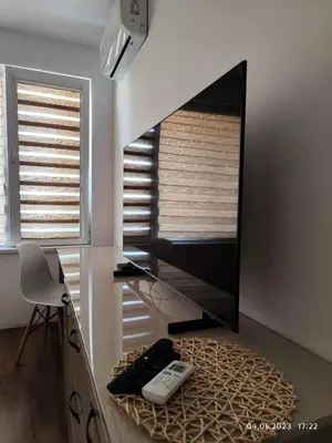 a living room with a flat screen tv and a chair at DeTY's Apartment in Burgas City