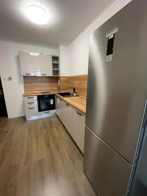 a kitchen with a stainless steel refrigerator and wooden floors at DeTY's Apartment in Burgas City
