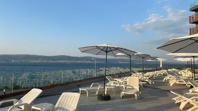 a row of white chairs and umbrellas on a patio at PARADISO 'В' 107 Private Cozy Studio NESSEBAR in Nesebar