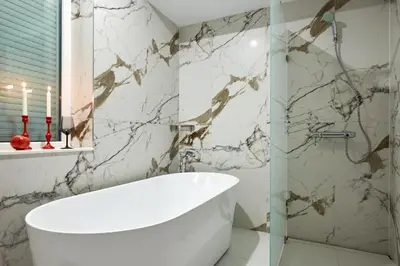 a bathroom with a white tub and marble walls at Premium Luxury SeaSide Apartment in Burgas City