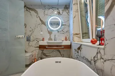 a bathroom with a tub and a sink and a mirror at Premium Luxury SeaSide Apartment in Burgas City