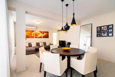a dining room and living room with a table and chairs at ЛУКСОЗНА ТРИЕТАЖНА КЪЩА в центъра на Приморско in Primorsko