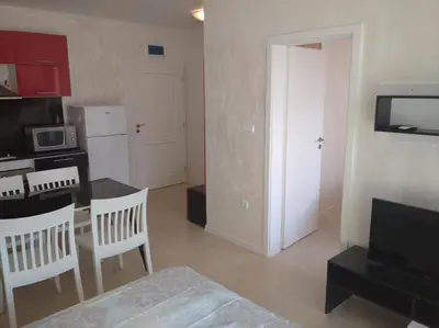 a living room with a kitchen and a table with chairs at Niya Apartments Kavaci Sozopol in Sozopol