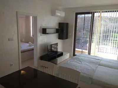a bedroom with a bed and a table and a window at Niya Apartments Kavaci Sozopol in Sozopol