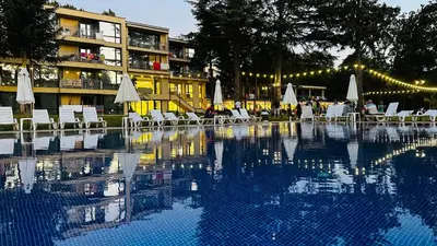 a swimming pool with chairs and umbrellas next to a building at Queen Nelly Park in Kiten