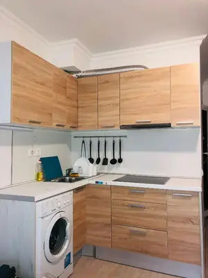 a kitchen with wooden cabinets and a washing machine at Apartments Sarafovo in Burgas City
