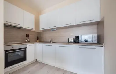 a white kitchen with white cabinets and a microwave at Stoyanov South Bay - Varna in Varna City
